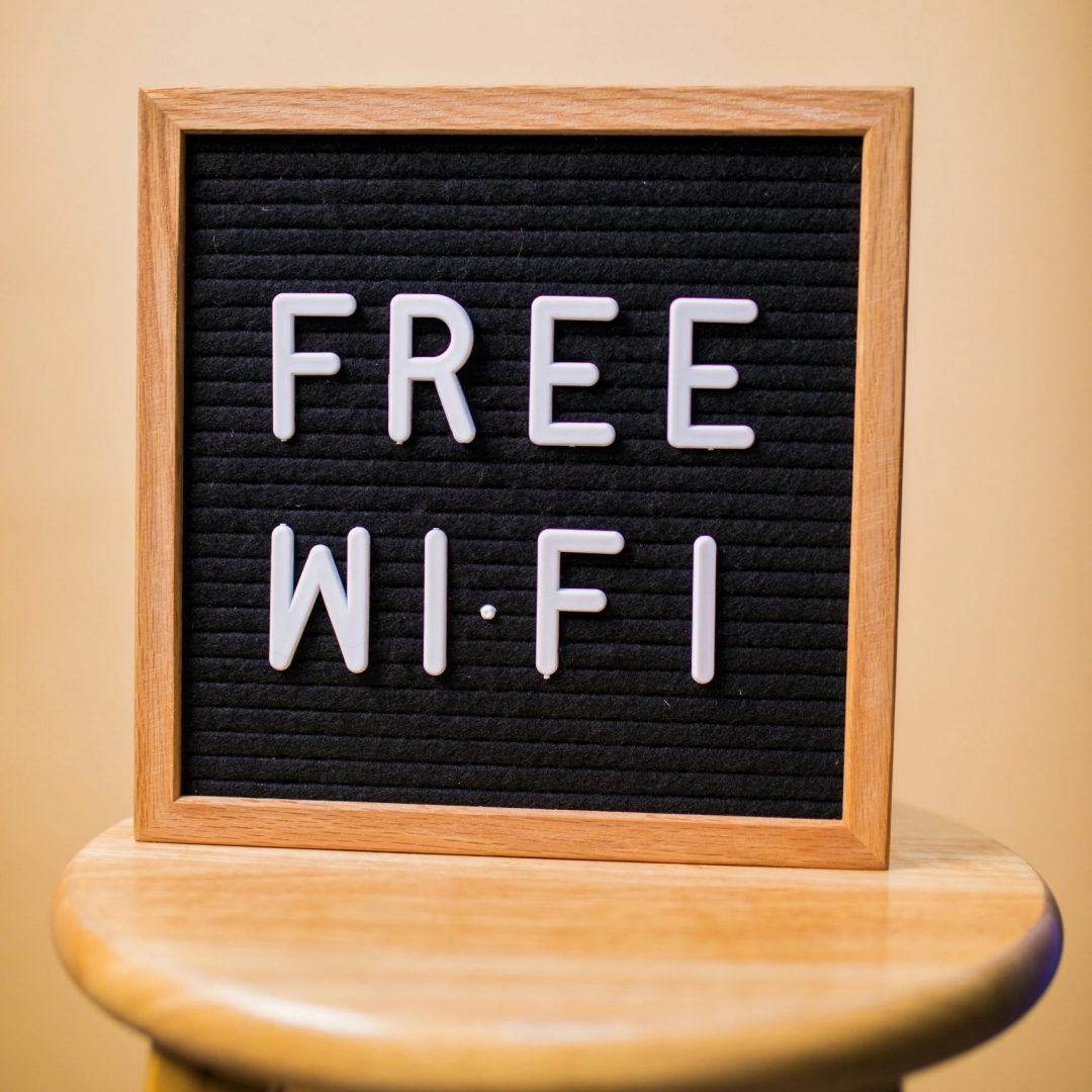 Letterboard displaying 'Free Wi-Fi' on a wooden stool in an indoor setting.